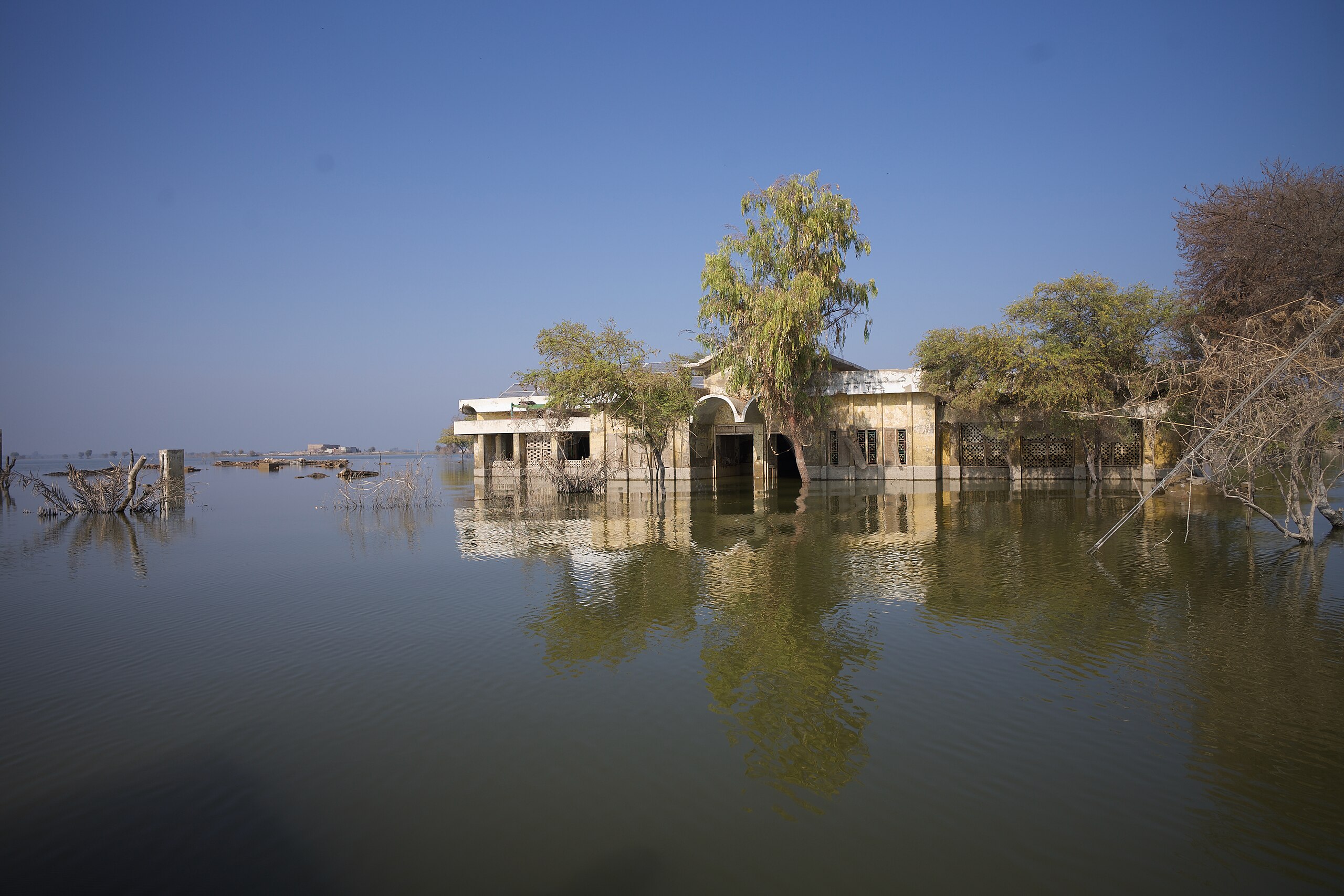 A partially submerged building surrounded by water stretching out into the distance.