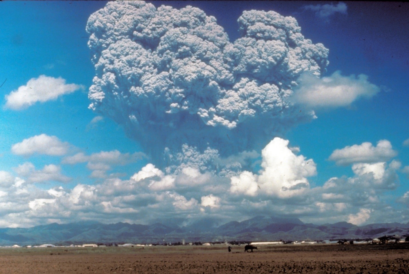 The smoke plume from a large volcanic eruption, reaching high above the clouds.