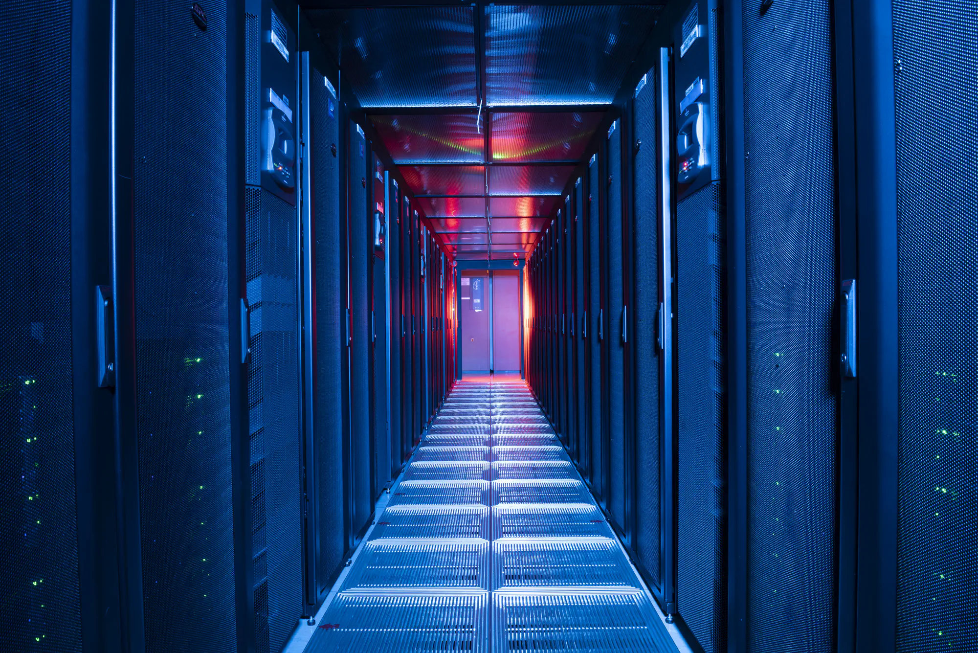 A corridor in a high-tech facility with metal grates along the walls, covering electronics.