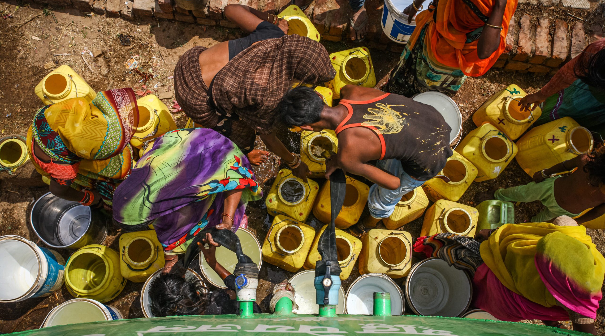 People over many buckets by a water tanker