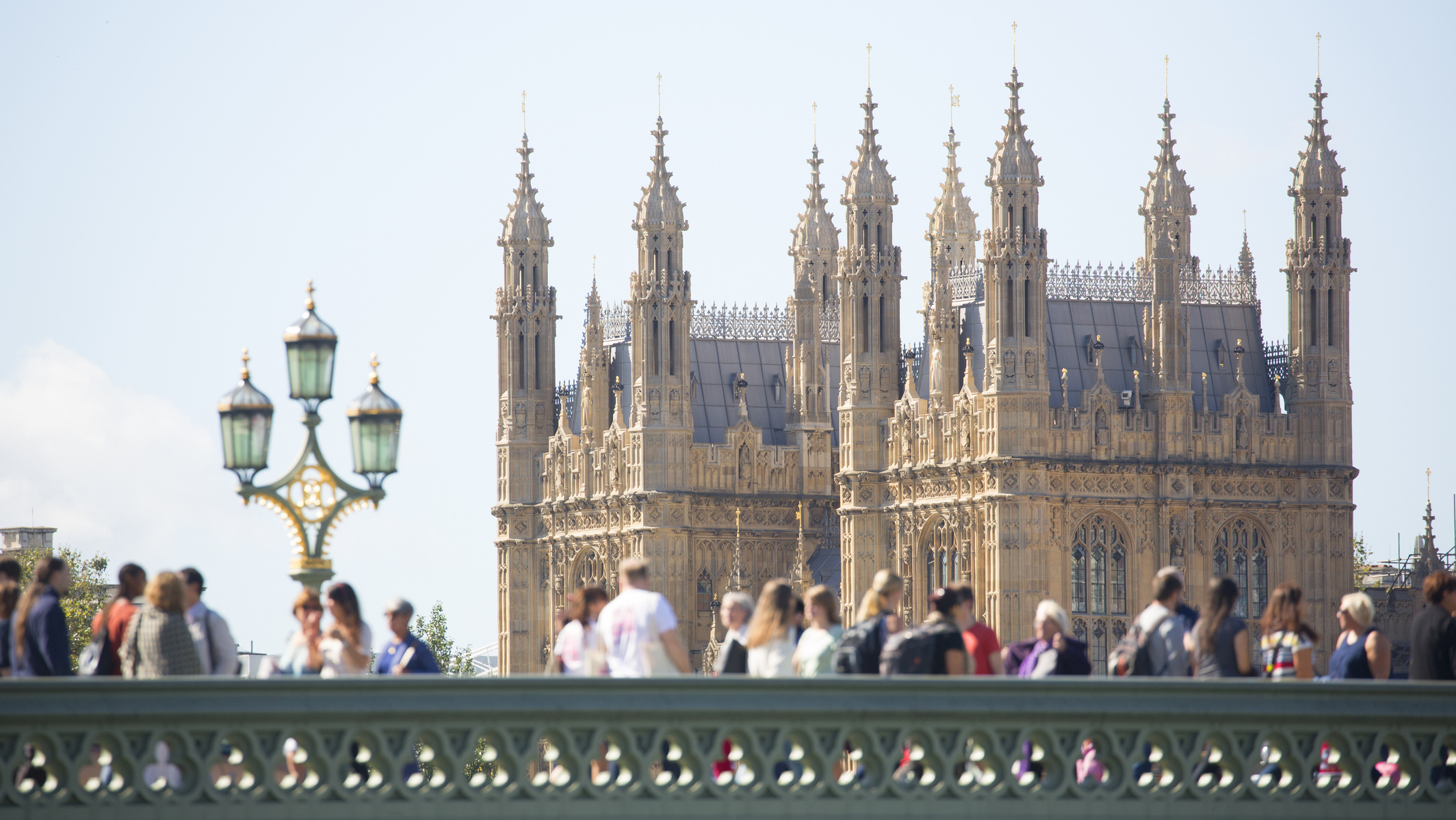 People crossing Westminster bridge with house of commons building background.