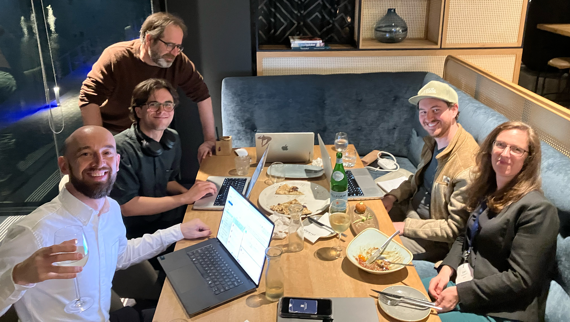 People around a table eating and working on laptops